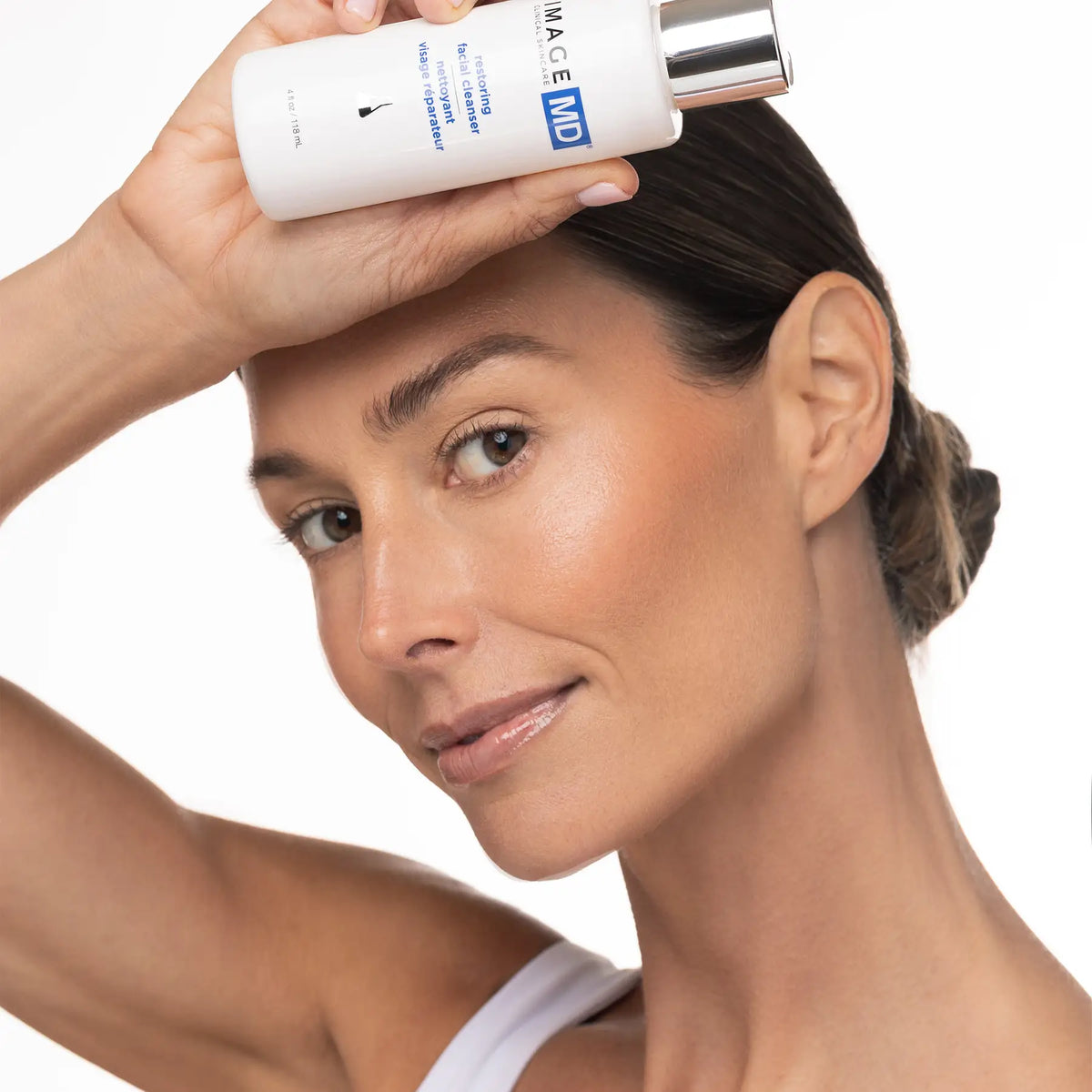 IMAGE Skincare MD Restoring Facial Cleanser held by a model with fresh, clean skin