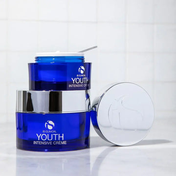 iS Clinical Youth Intensive Crème – Anti-Ageing Peptide Moisturiser 50g / 100g in blue jars on a countertop.