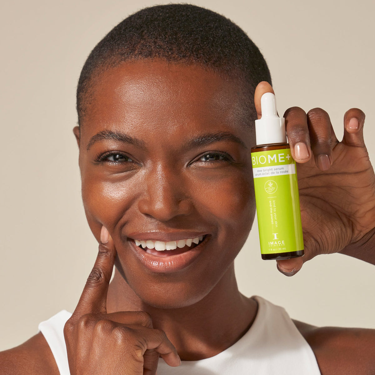 IMAGE Skincare BIOME+ Dew Bright Serum model holding the bottle with a dewy complexion