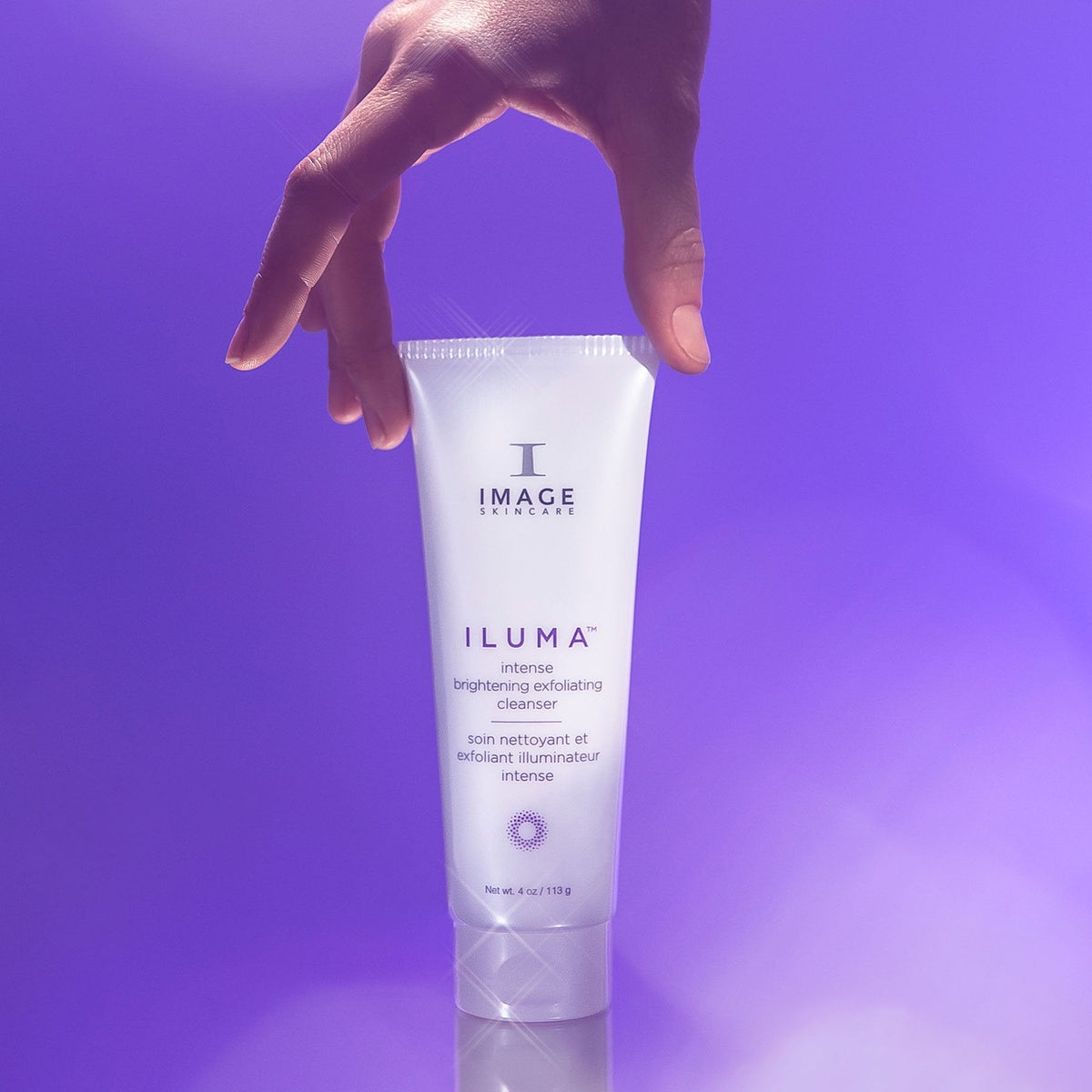 IMAGE Skincare ILUMA Intense Brightening Exfoliating Cleanser tube held against a purple background