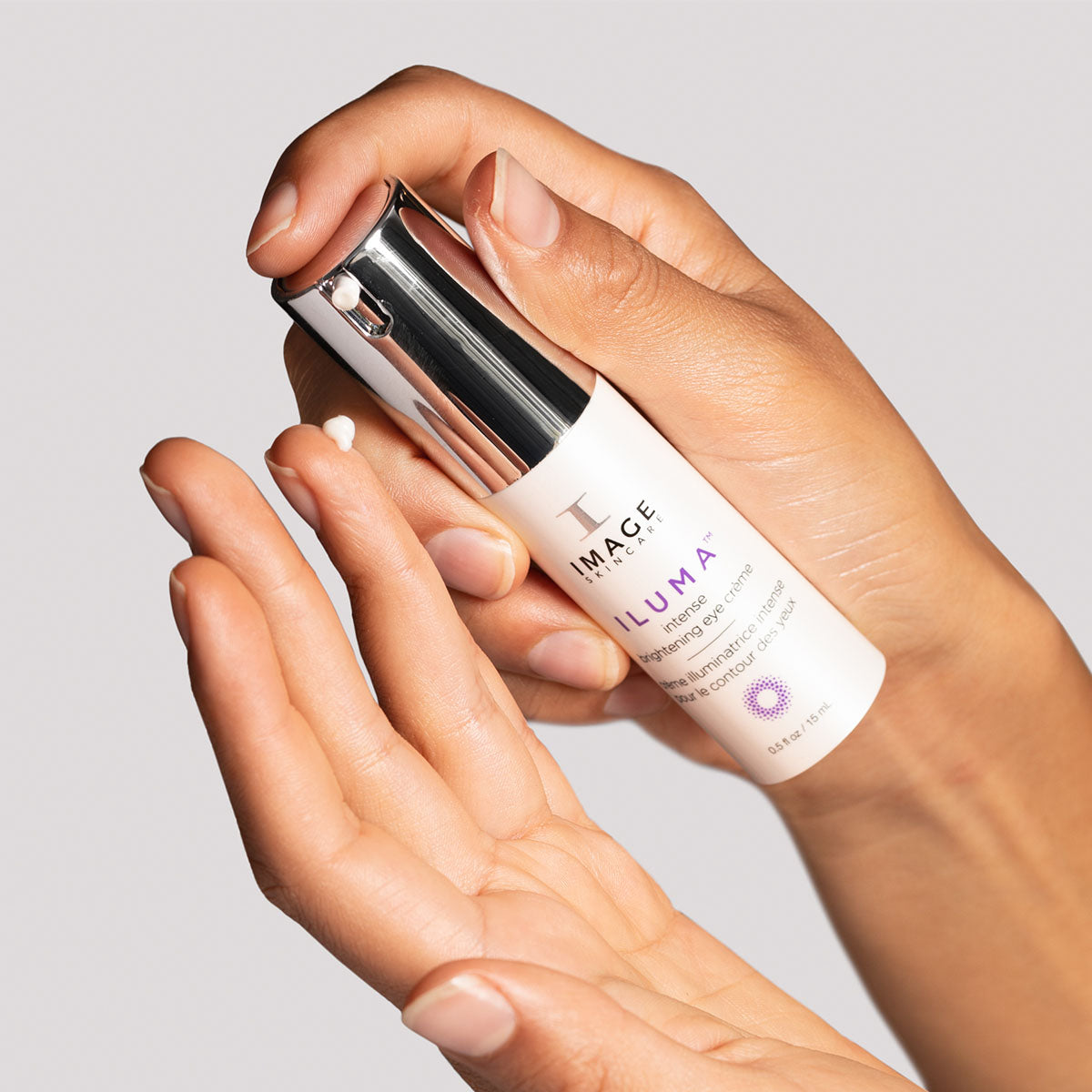 IMAGE Skincare ILUMA Intense Brightening Eye Crème pump dispensing eye cream onto fingertip