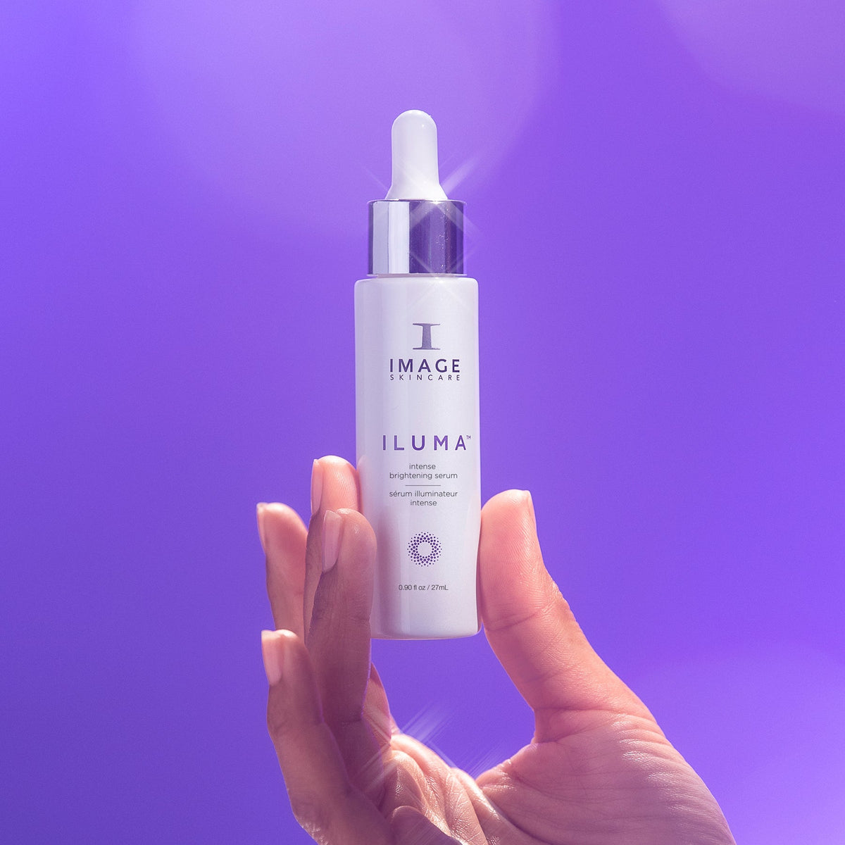 IMAGE Skincare ILUMA Intense Brightening Serum bottle held against a purple background