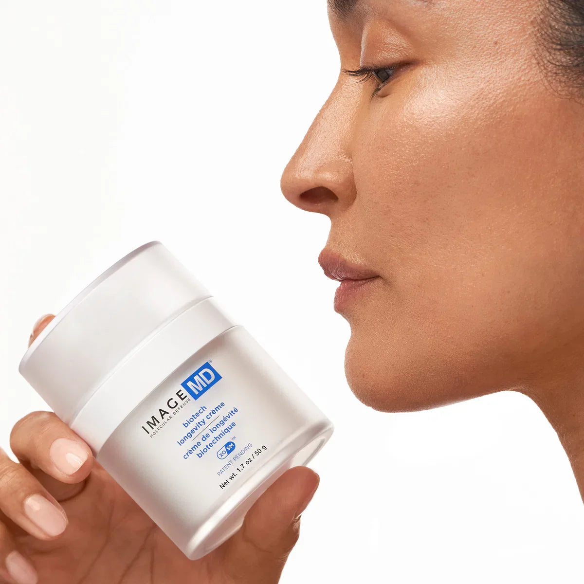 IMAGE Skincare MD Biotech Longevity Crème jar held by a model with radiant skin