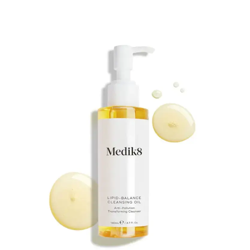 Medik8 Lipid-Balance Cleansing Oil pump bottle with golden oil droplets showing the silky texture