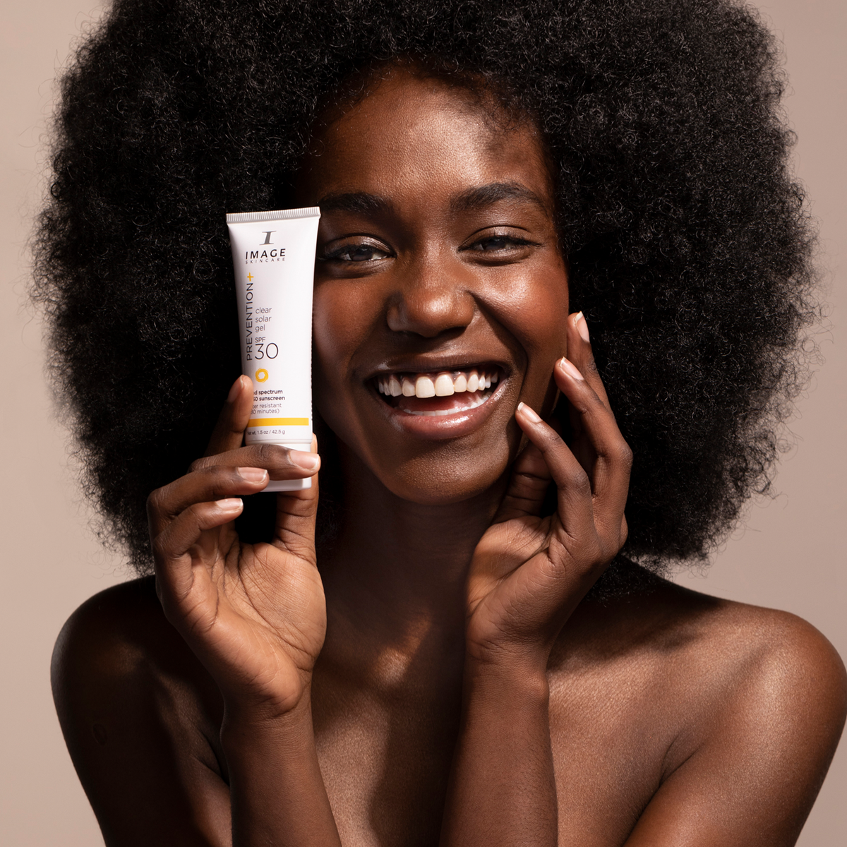 IMAGE Skincare PREVENTION+ Clear Solar Gel SPF 30 held by a smiling model