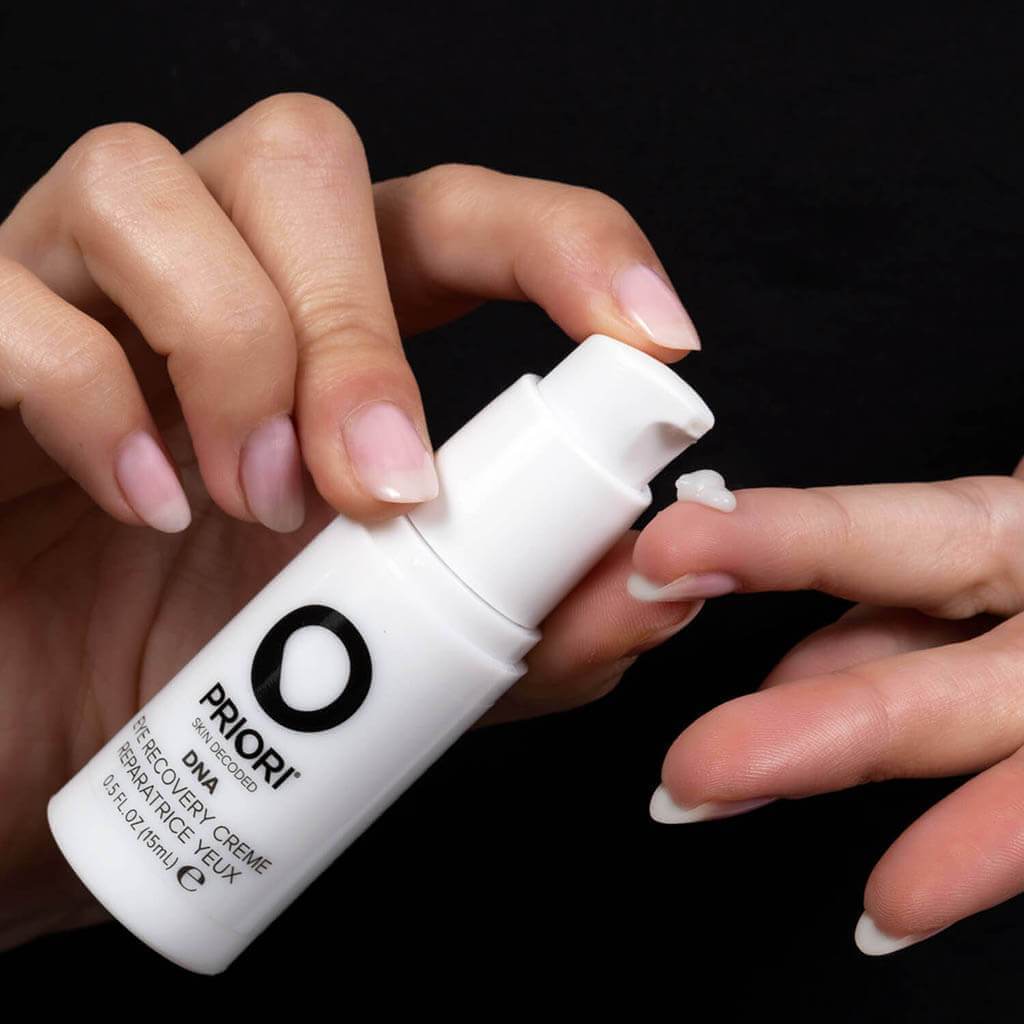 PRIORI DNA Eye Recovery Crème pump bottle held in the hand