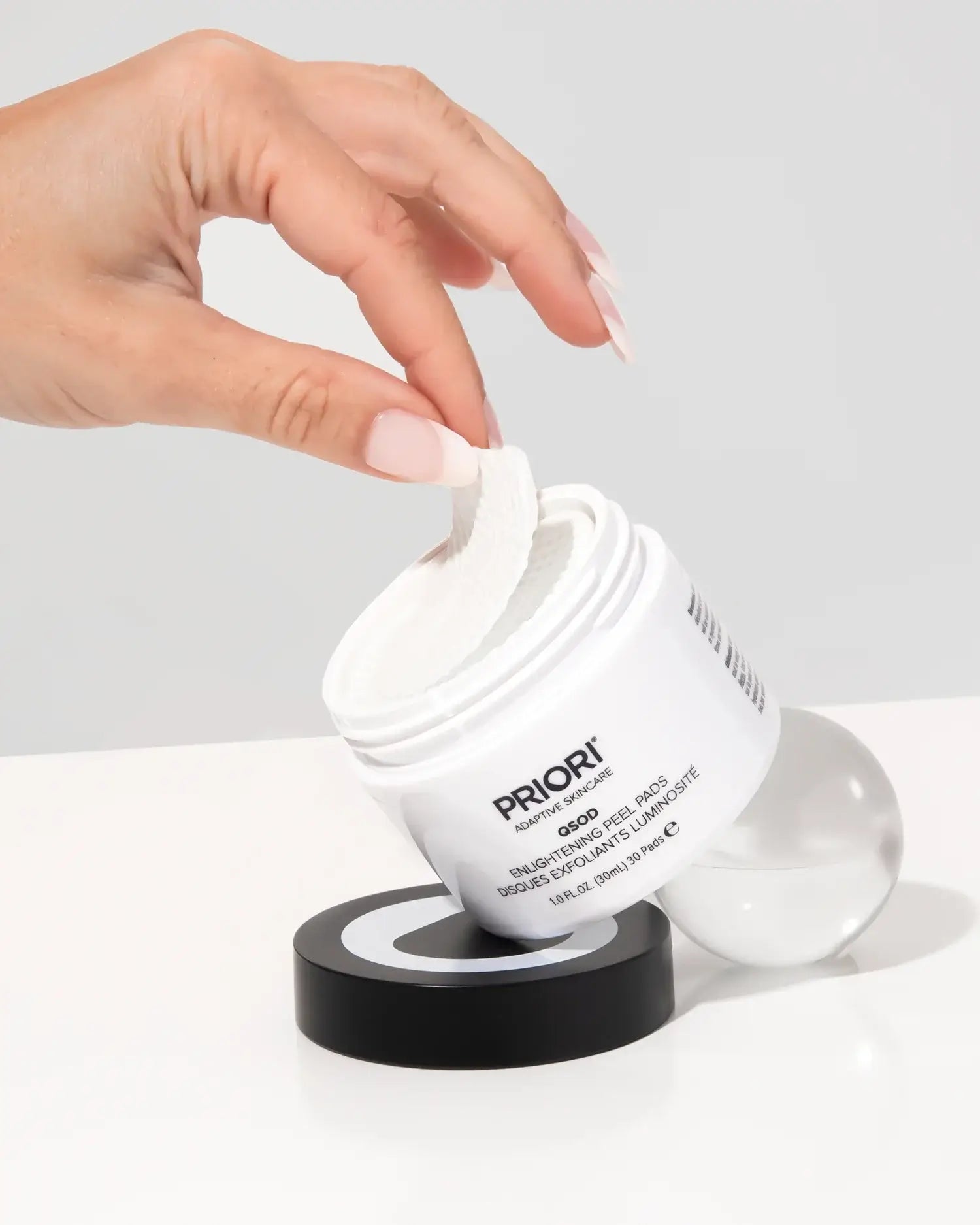 Person using PRIORI Q+SOD Enlightening Peel Pads, showcasing the product and its easy application.