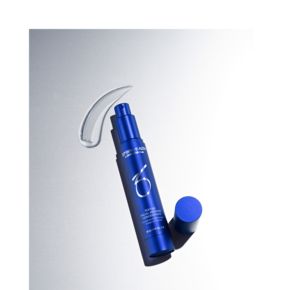 ZO Skin Health Peptide Facial Refining Concentrate in blue bottle with serum drop on silver background.