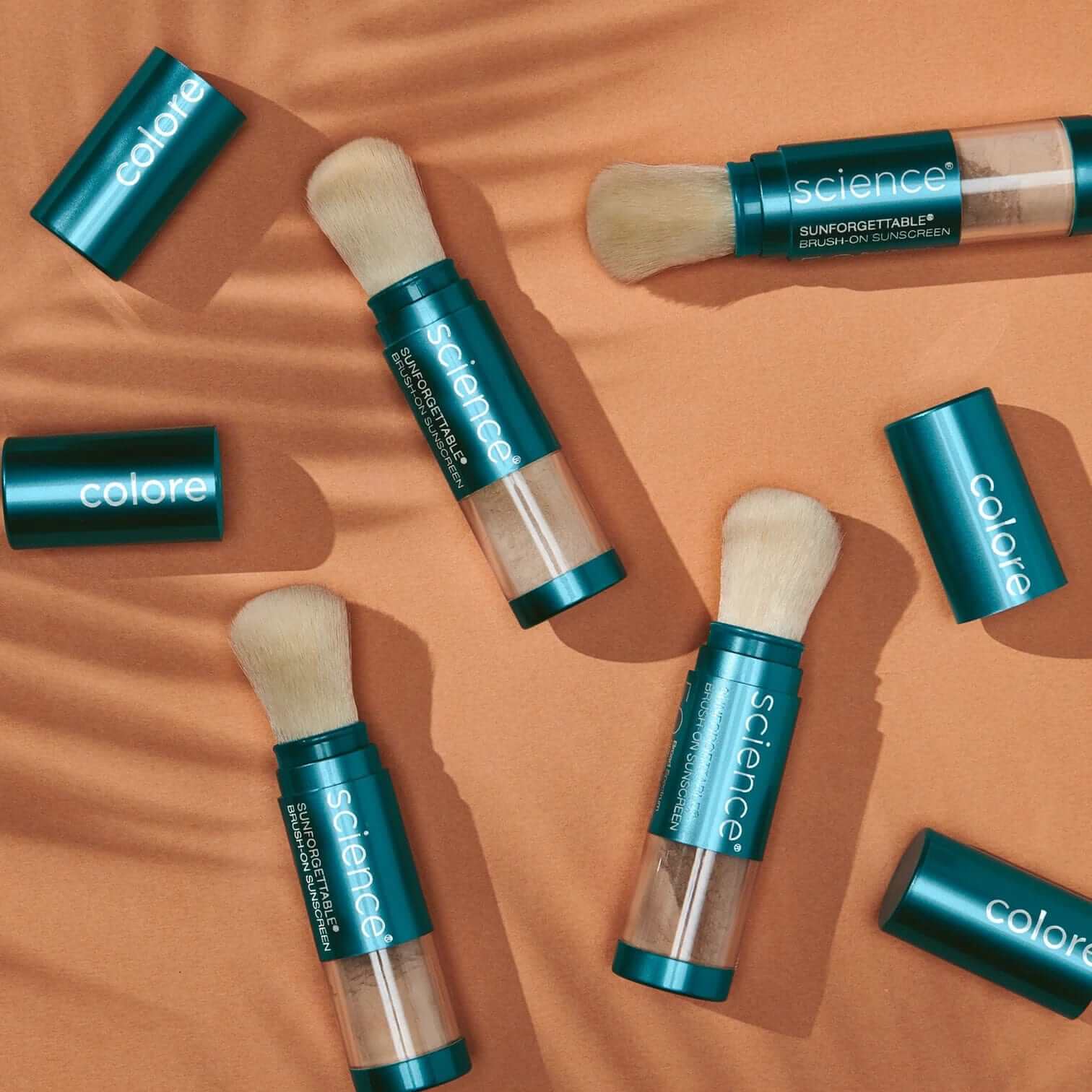 Colorescience® Sunforgettable ™ Total Protection Brush-On Shield SPF 50 on a sandy surface, showcasing product packaging.