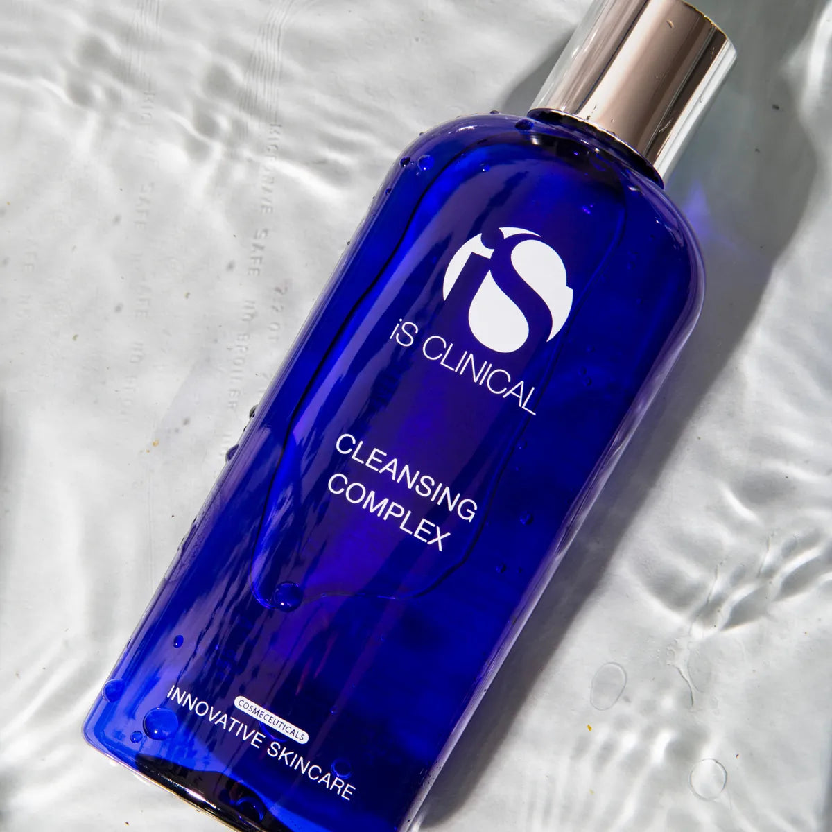 iS Clinical Cleansing Complex 180ml bottle on a rippled white surface