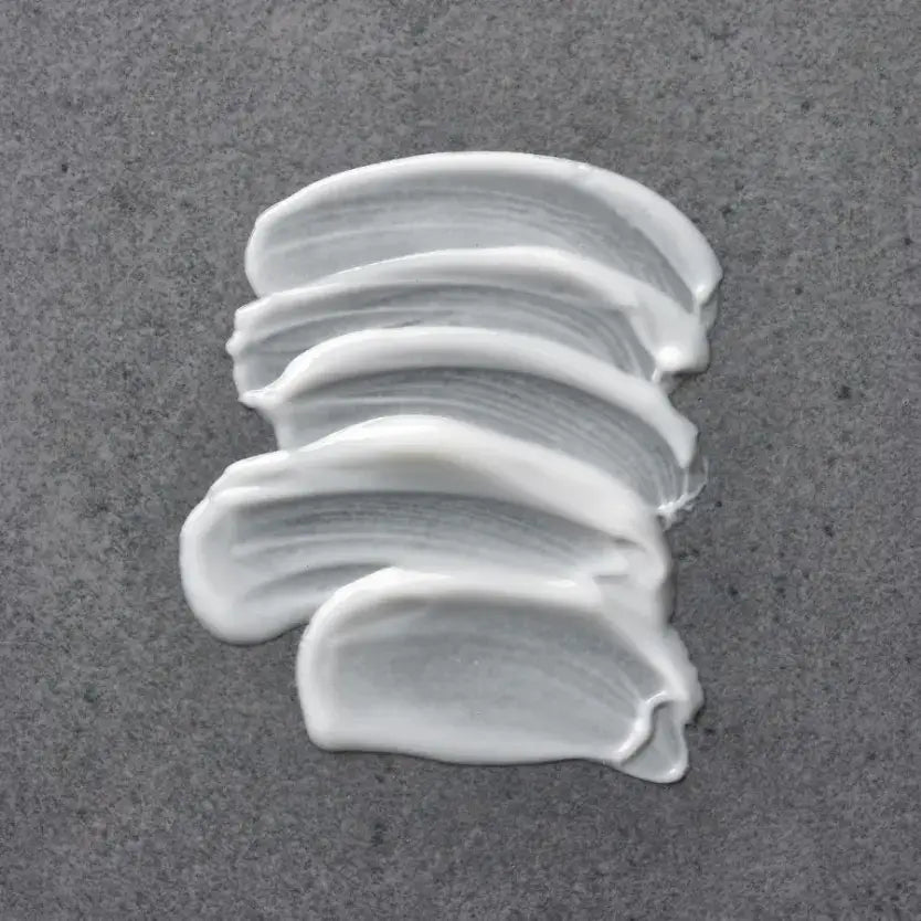 Creamy texture of Medik8 Physical Sunscreen SPF 50+™ on a gray background.